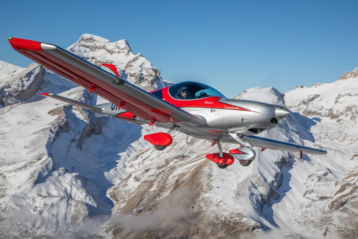 Bristell B23 banking over snow-covered peaks