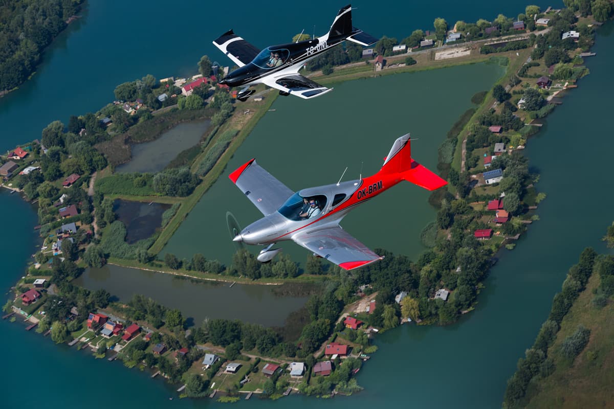 Two Bristell B23s in formation over a lake