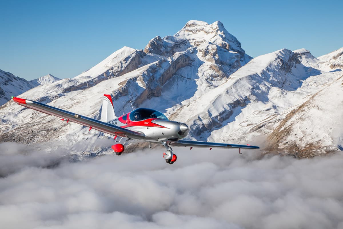 Bristell B23 Mosaic above the clouds beside a snow-capped peak