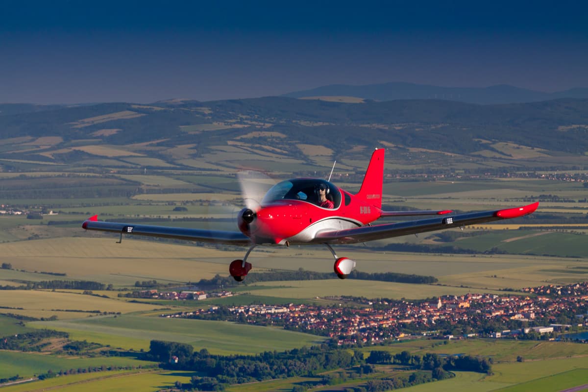 Red Bristell TDO cruising over a wide valley at golden hour